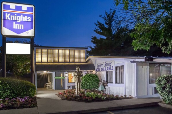A Knights Inn with a signboard, a statue, and a building with a sign for 'Vacuzzi Rooms Now Available'.