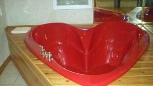 Una bañera roja con forma de corazón en una habitación de madera.