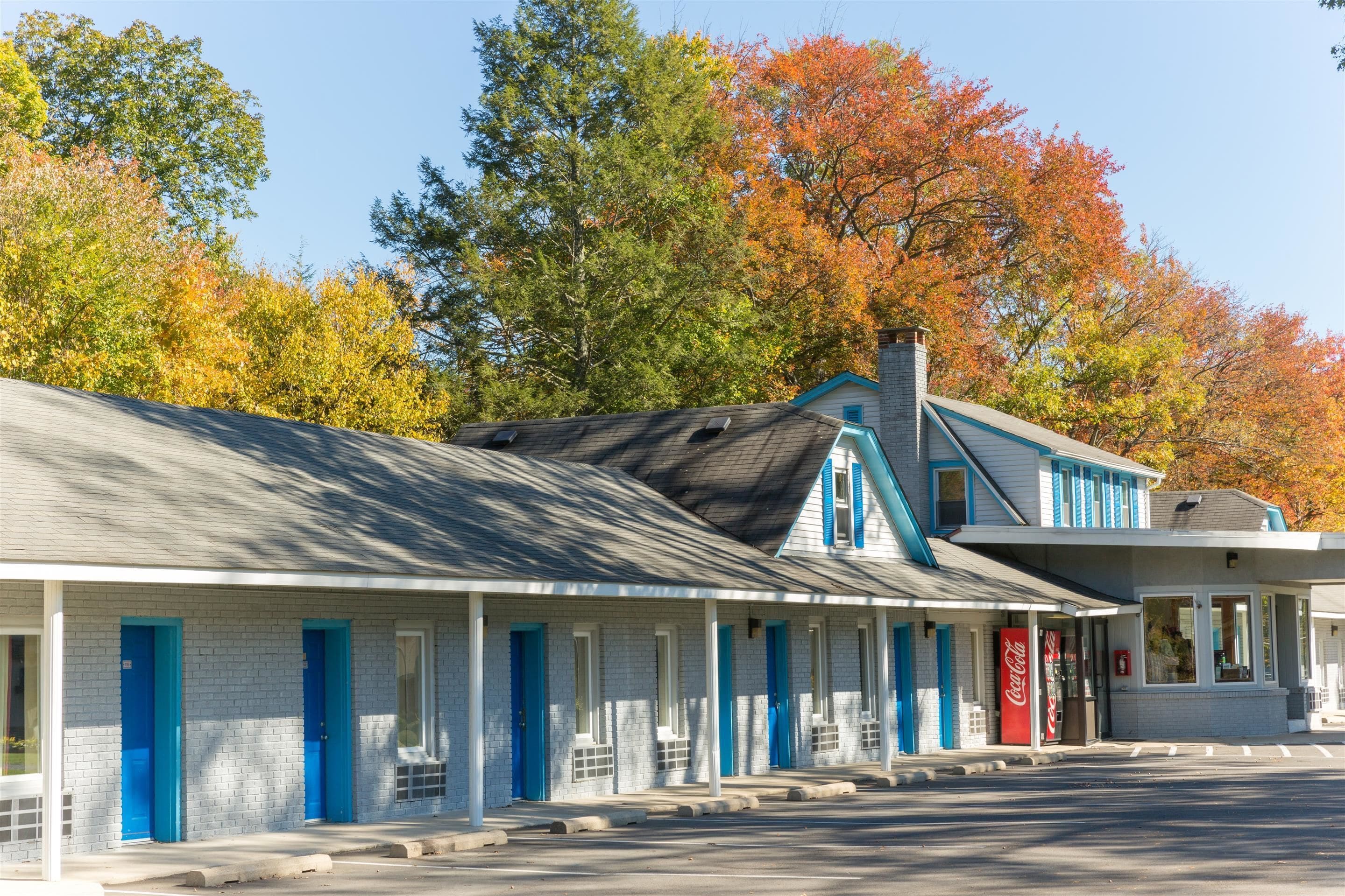 A motel with a row of rooms, each with a blue door and a window.