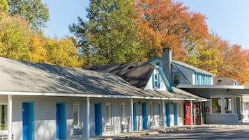 A motel with a row of rooms, each with a blue door and a window.