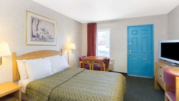 Una habitación de hotel con una cama, un escritorio, un televisor y una puerta.
