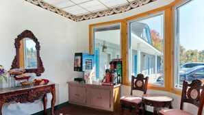 Una habitación con un espejo grande, una mesa de madera con un florero, una cafetera y vistas a un edificio.