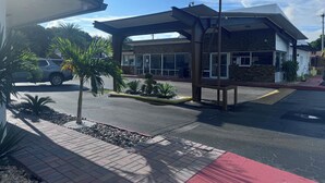 A building with a covered entrance, a parking lot, and a small garden area with plants. - Econo Lodge Inn & Suites Florida City (Florida City)