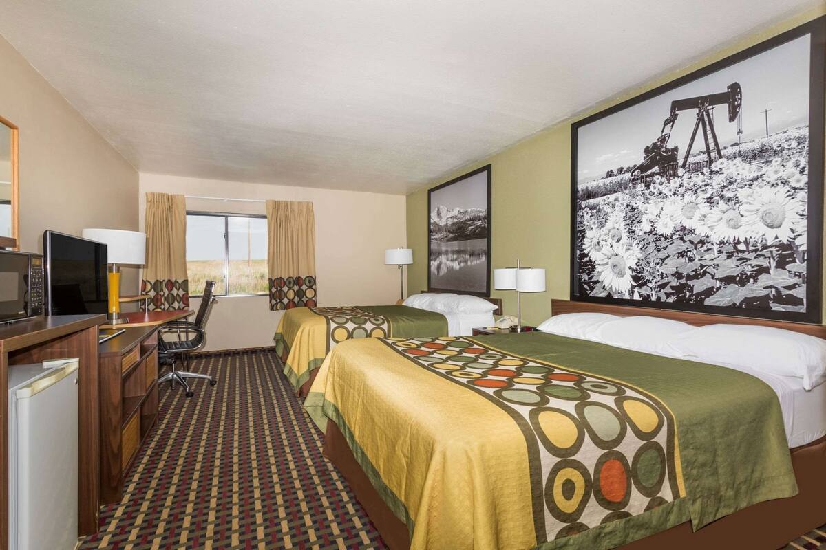 Une chambre d’hôtel avec deux lits, un bureau avec un ordinateur, un four à micro-ondes et un réfrigérateur.