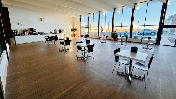 Uma sala de jantar ampla, com pé direito alto e grandes janelas que oferecem vista para o exterior.