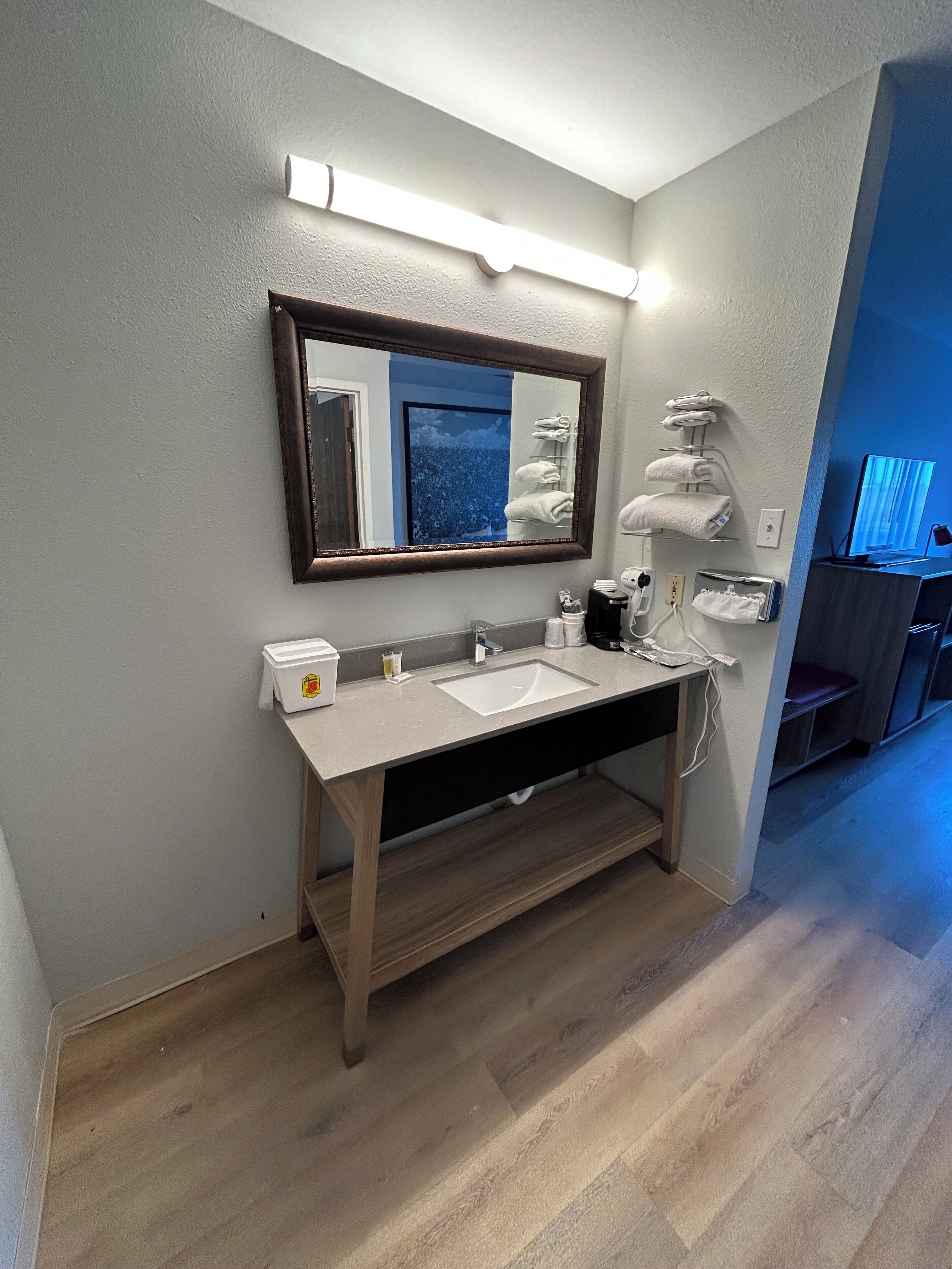 Un baño moderno con tocador de madera, un espejo grande y un calefactor empotrado.