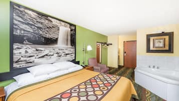 A hotel room with a bed, a large wall mural, a bathroom with a bathtub, and a door leading to another room.