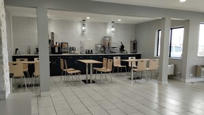 A modern kitchen with a central island, black cabinets, and a seating area with chairs and tables.
