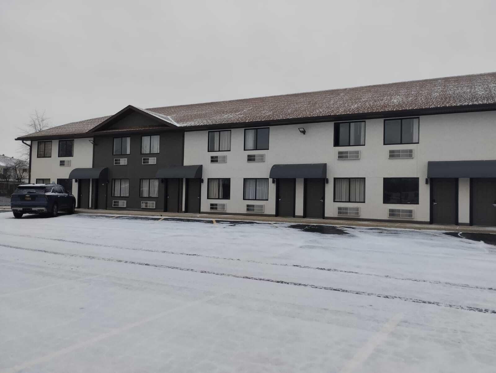 A multi-story building with a flat roof and a parking lot in front.