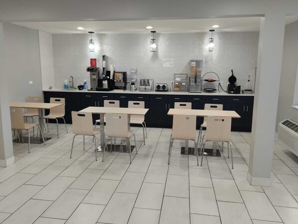 Una cocina moderna con una isla central, electrodomésticos integrados y una zona de comedor con sillas y mesas.