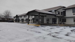 A row of motel buildings with a covered parking area and a snow-covered ground.