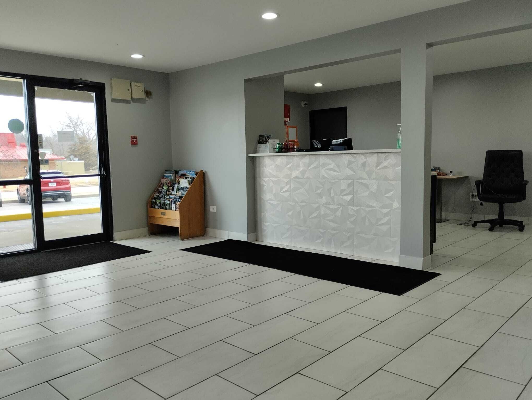 A reception area with a check-in counter, a wooden magazine rack, and a black office chair.