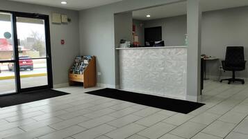 A reception area with a check-in counter, a wooden magazine rack, and a black office chair.
