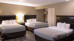 Una habitación de hotel con dos camas, una mesita de noche con lámpara y un armario.