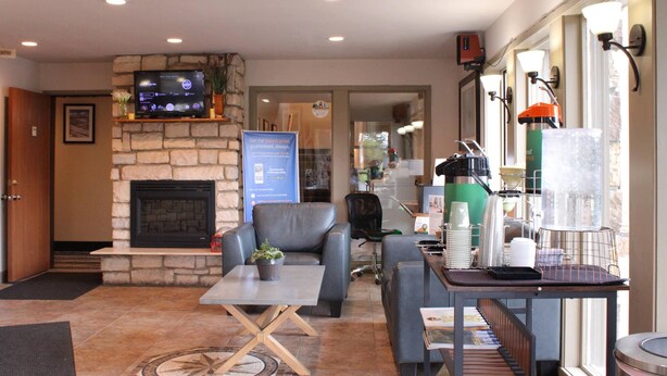 Un vestíbulo con chimenea de piedra, un televisor montado en la pared y una mesa de recepción con estación de café.