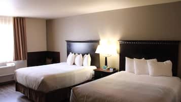 Habitación de hotel con dos camas, una mesita de noche con lámpara y una ventana con cortinas.