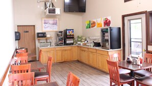 Un restaurante con mobiliario de madera, una zona de cocina y un televisor fijado a la pared.