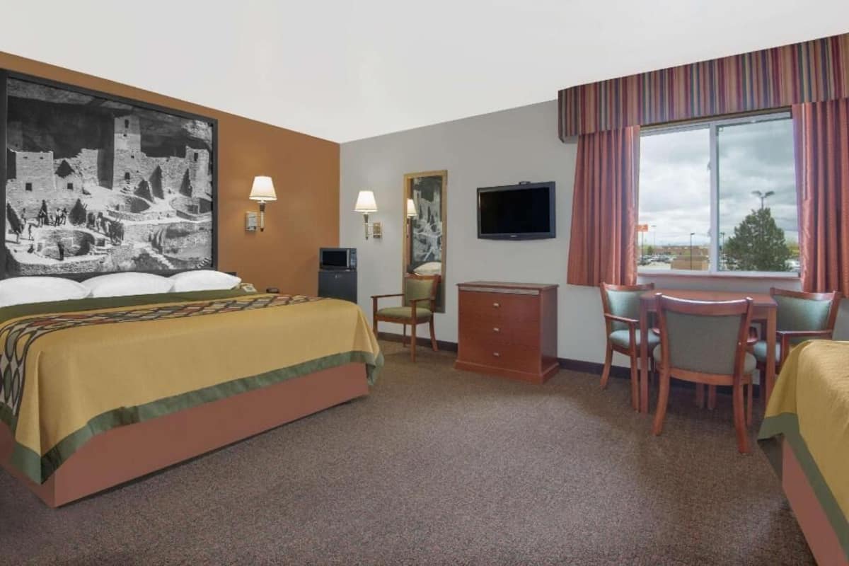 Une chambre d’hôtel avec un lit, un bureau, une chaise, une télévision et une fenêtre.