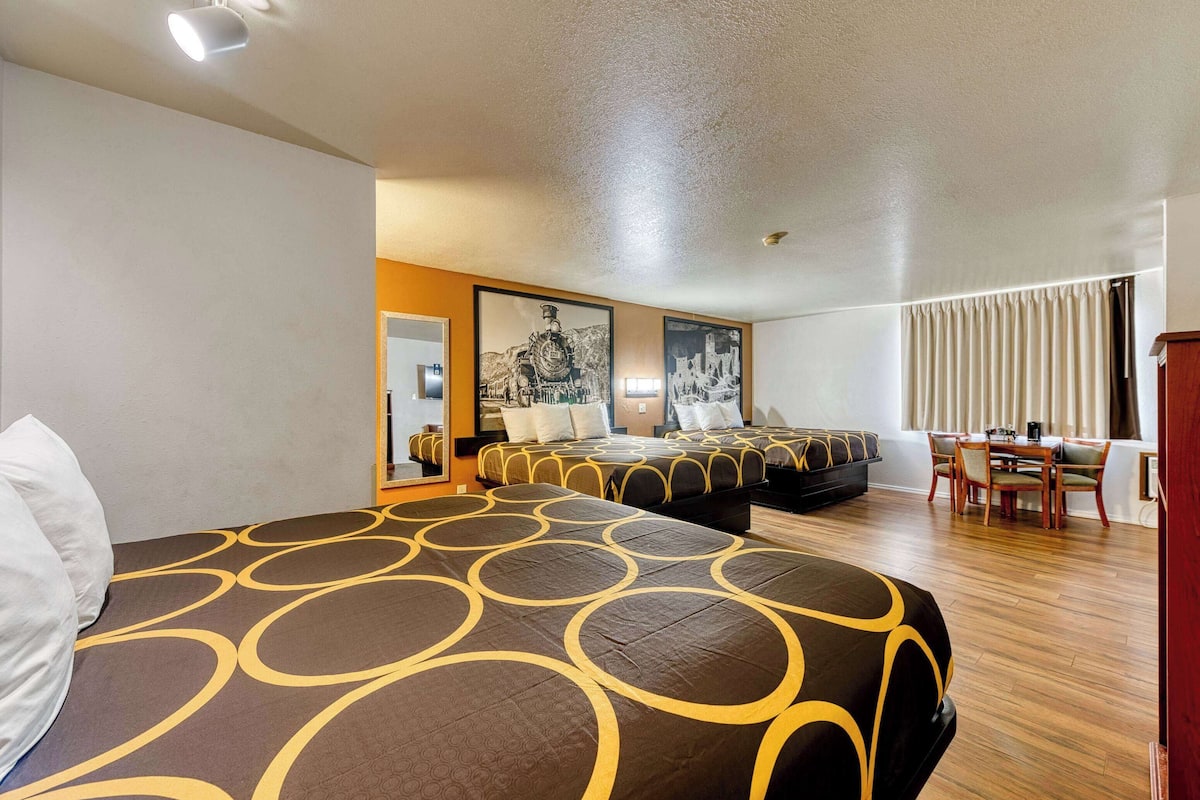 Une chambre d’hôtel avec deux lits, un coin repas et des œuvres d’art accrochées aux murs.