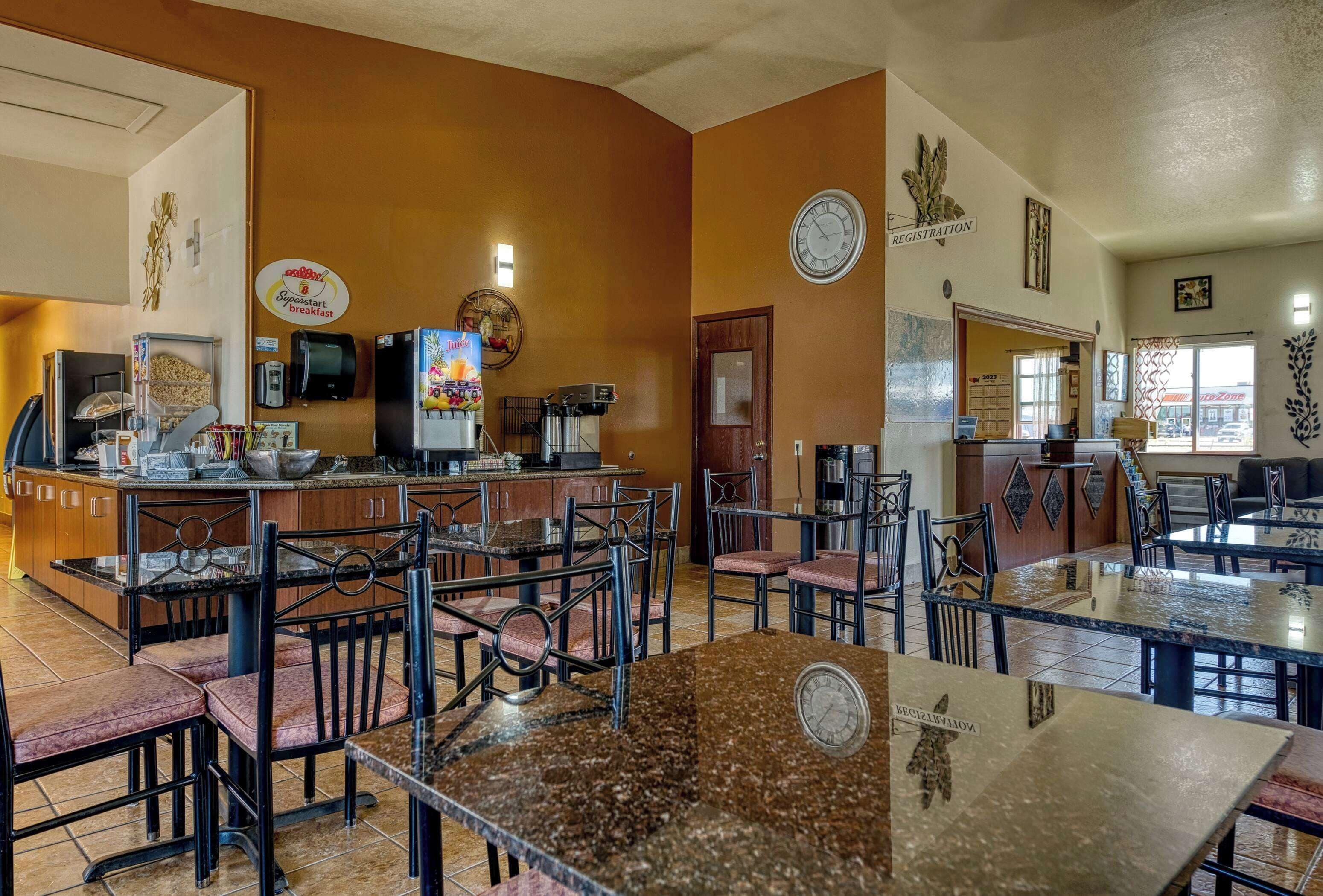 A restaurant with a buffet area, multiple dining tables, and chairs.