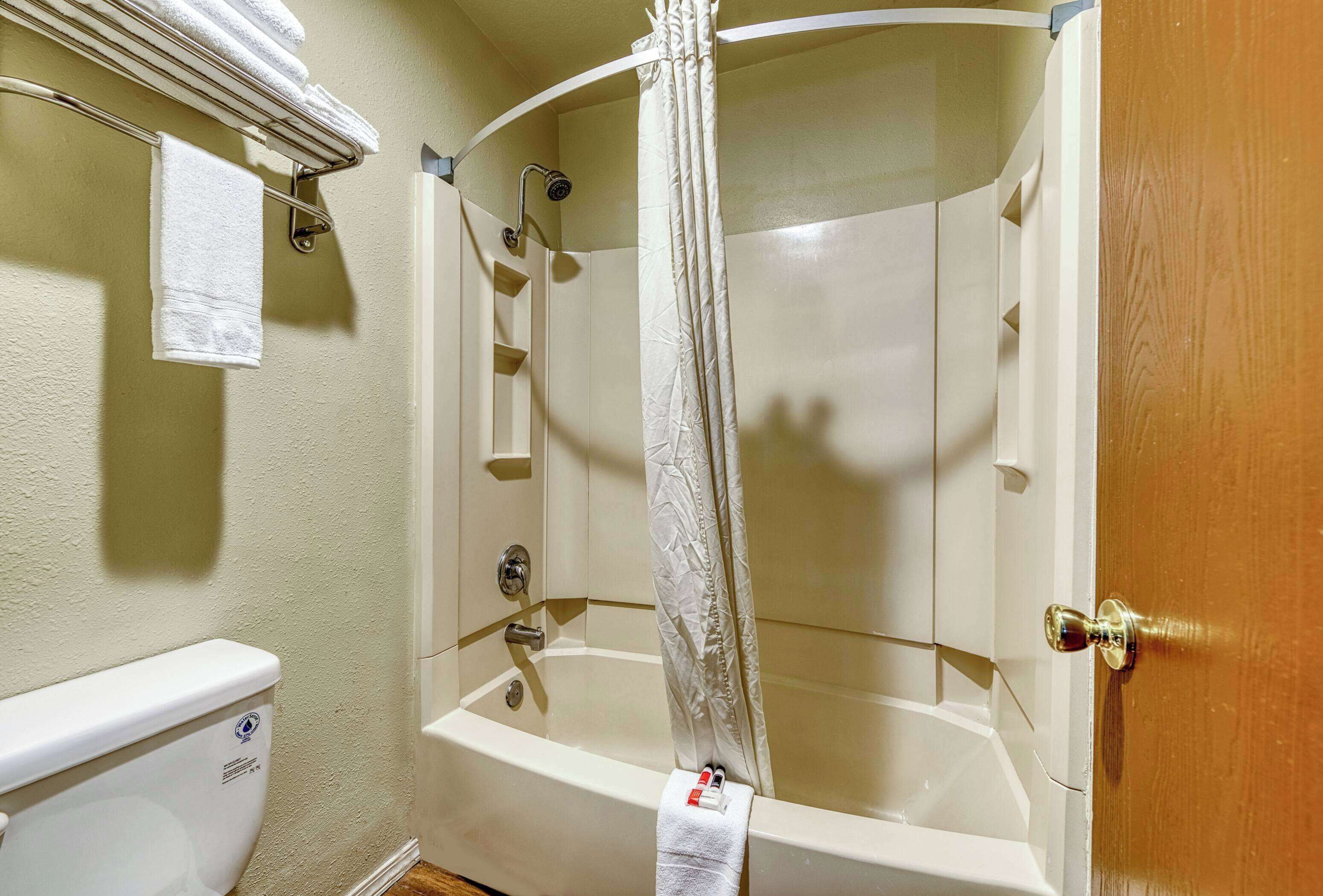 Ein Badezimmer mit Badewanne, Duschvorhang, Handtuchhalter und Toilette.