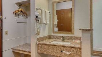 A bathroom with a granite countertop sink, a mirror, a towel rack, and a hairdryer.