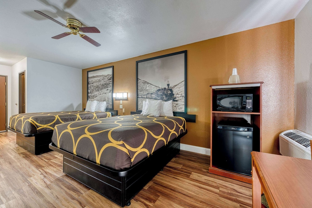 Une chambre d’hôtel avec deux lits, un ventilateur de plafond, un four à micro-ondes et un petit réfrigérateur.