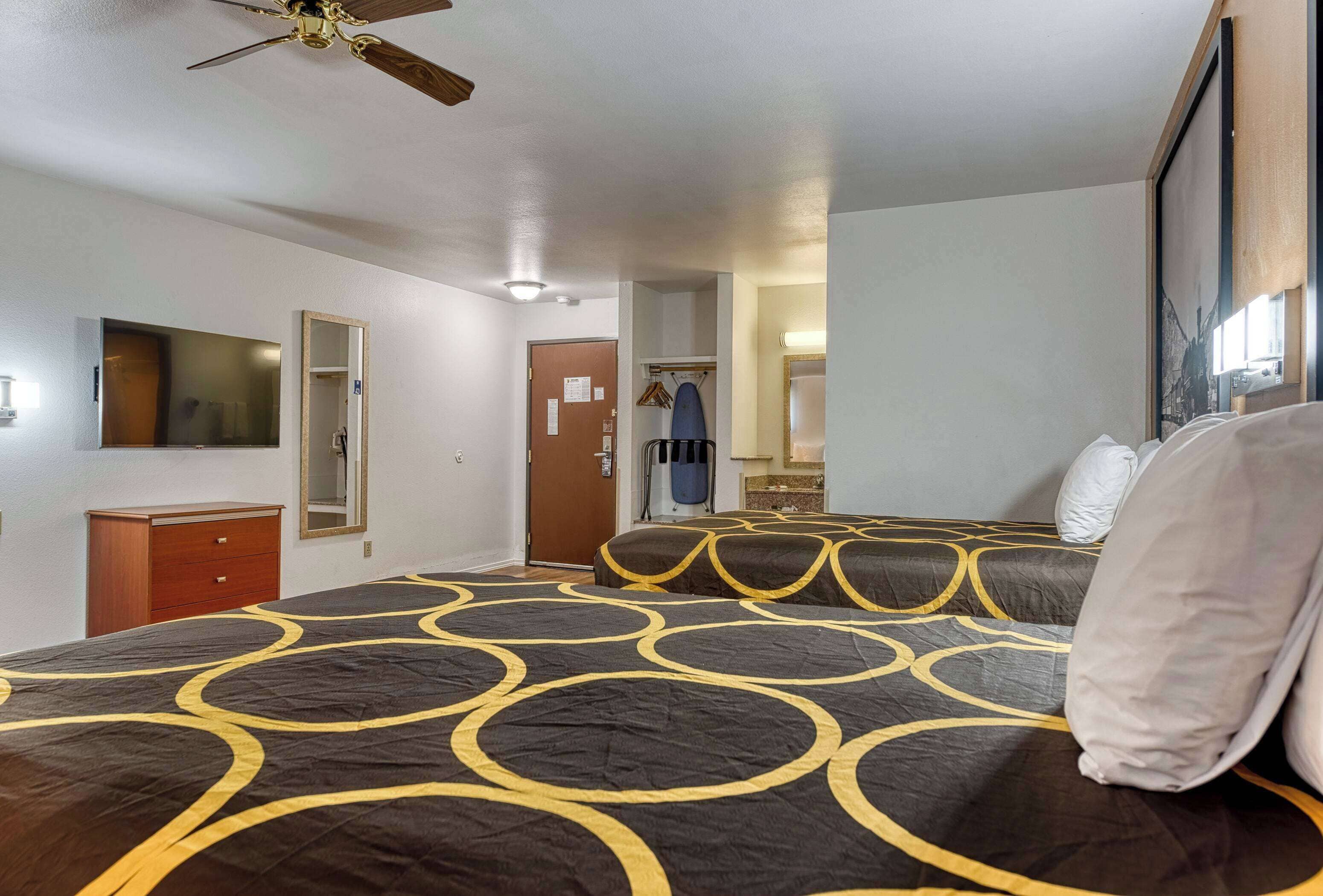 Habitación de hotel con una cama grande, un ventilador de techo, un aparador y un espejo.