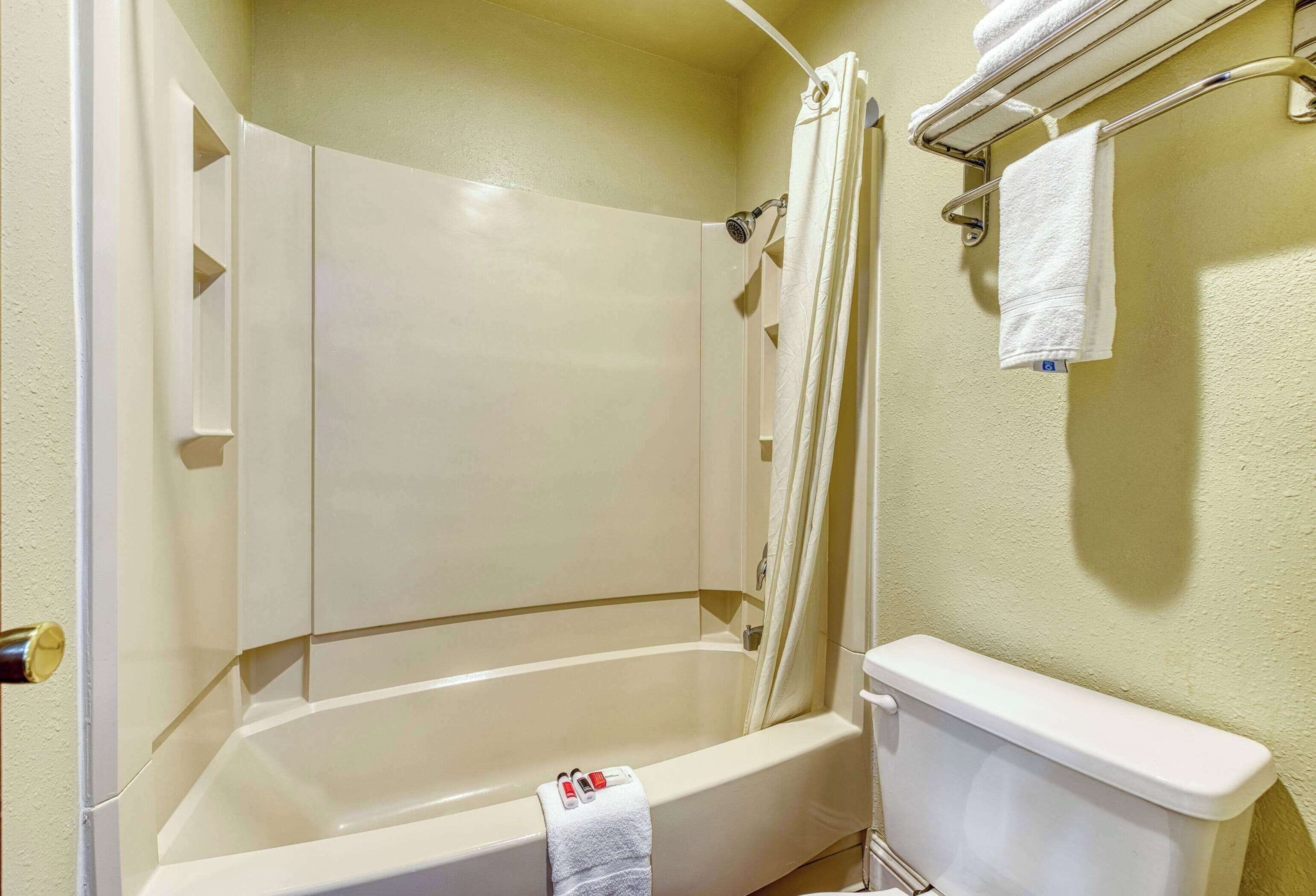 A bathroom with a bathtub, toilet, and towel rack.