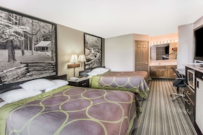 A hotel room with two beds, a desk, a mirror, and a bathroom with a sink and mirror.