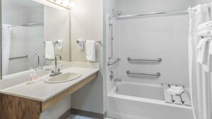 A bathroom with a sink, mirror, and shower.
