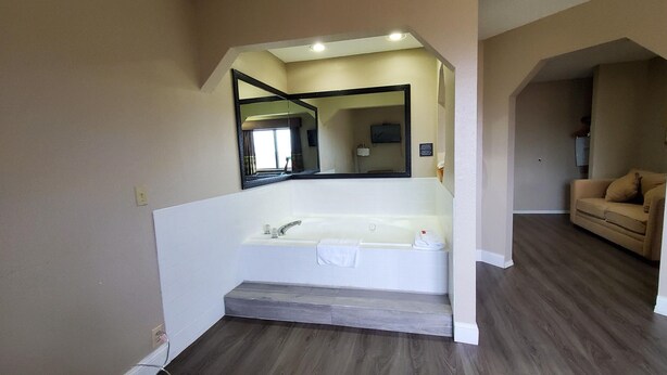 A bathroom with a large mirror, a bathtub, and a wooden floor. - Super 8 by Wyndham Paris (Paris)
