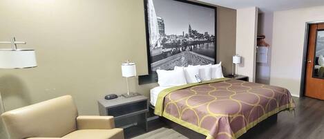 Een hotelkamer met een bed, een stoel, een bureau, een lamp en een stadsgezichtschilderij aan de muur.
