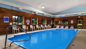 An indoor swimming pool with a wooden wall, a metal pool ladder, and several white lounge chairs. - Super 8 by Wyndham Paris (Paris)