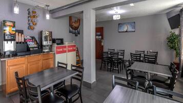 Un restaurant avec un comptoir, des machines à café et une pancarte indiquant « Merci ». Des tables et des chaises sont disposées pour accueillir les clients.