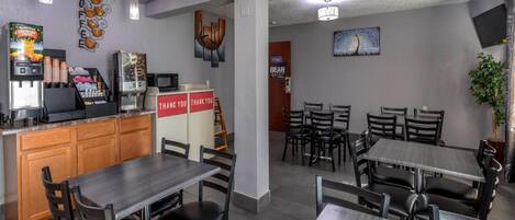 A restaurant with a counter, coffee machines, and a 'Thank You' sign. Tables and chairs are arranged for dining.