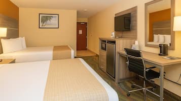 A hotel room with two beds, a desk, a chair, a television, a mirror, and a door leading to another room.