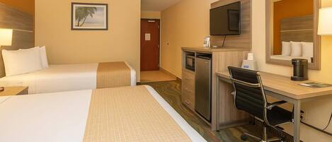 A hotel room with two beds, a desk, a chair, a television, a mirror, and a door leading to another room.