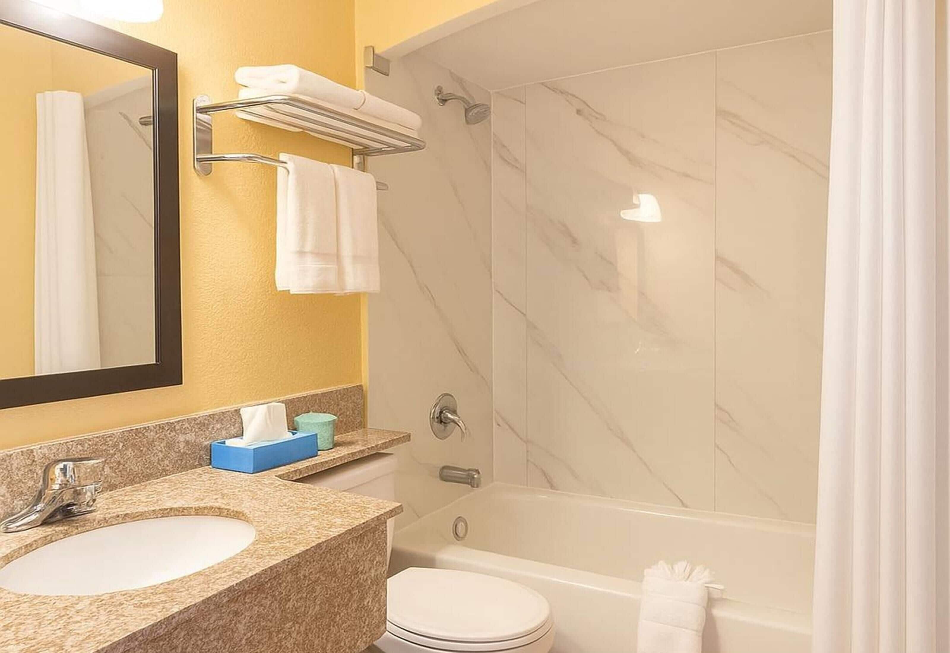 A bathroom with a marble shower, a sink, and a toilet.
