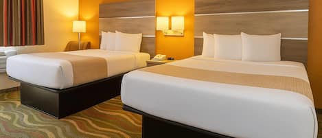 Habitación de hotel con dos camas, una mesita de noche y un teléfono, además de una alfombra estampada.