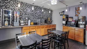 A modern kitchen with a checkered backsplash, a coffee machine, and a refrigerator. - Travelodge by Wyndham Muskegon (Muskegon)