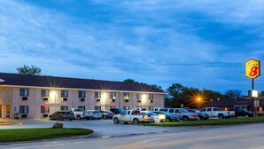 A Super 8 motel with multiple parking spaces, a well-lit exterior, and a clear sky.
