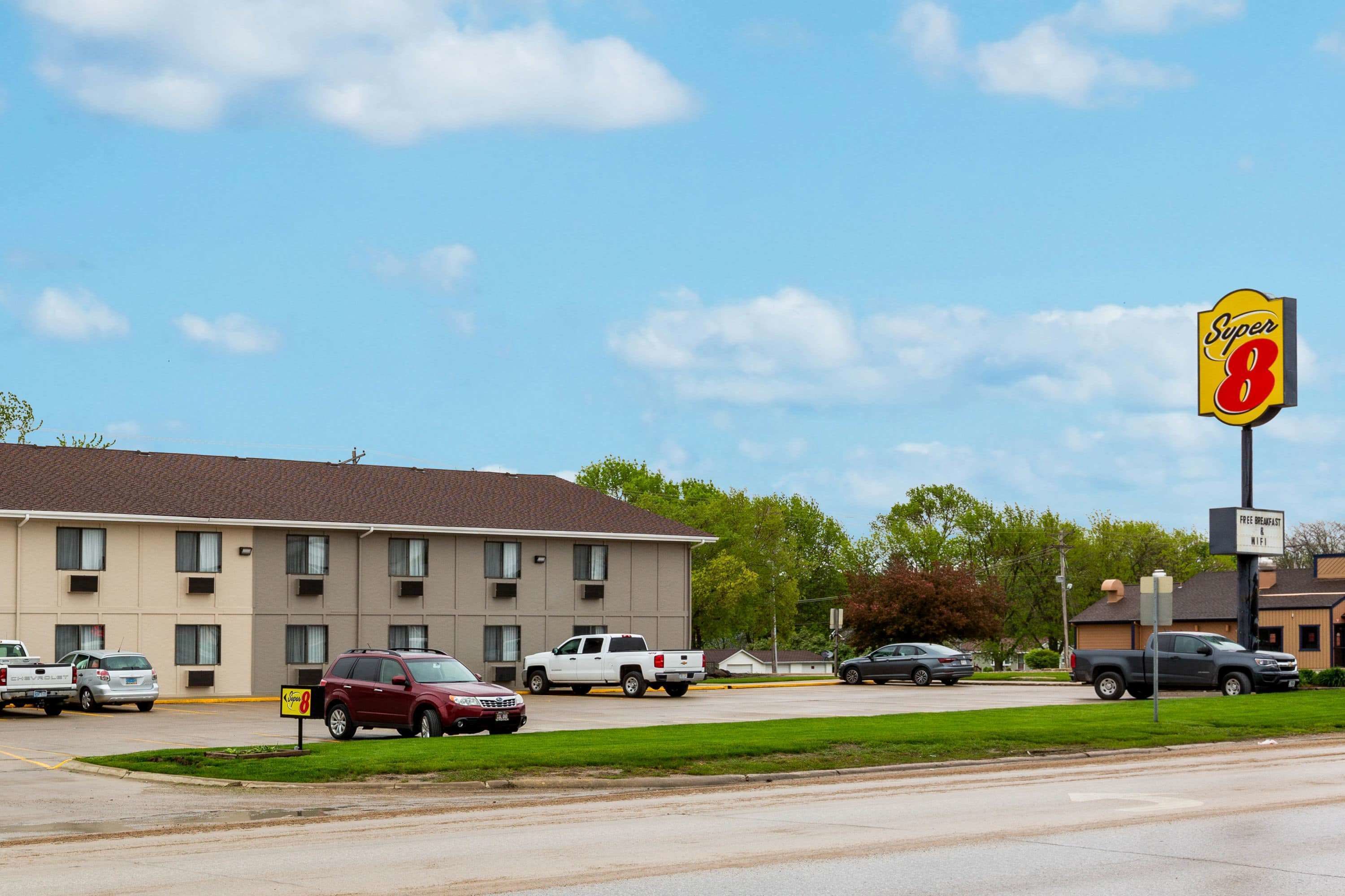 A Super 8 motel with a parking lot, a grassy area, and a clear sky.