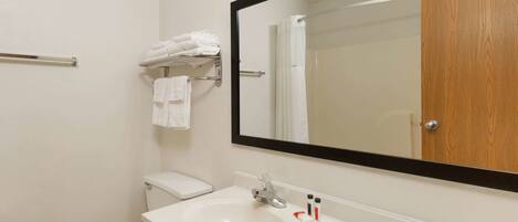 Une salle de bain avec un lavabo blanc, un miroir et des toilettes.