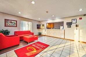 A hotel lobby with a red sofa, a reception desk, and a tiled floor. - Econo Lodge Maquoketa (Maquoketa)