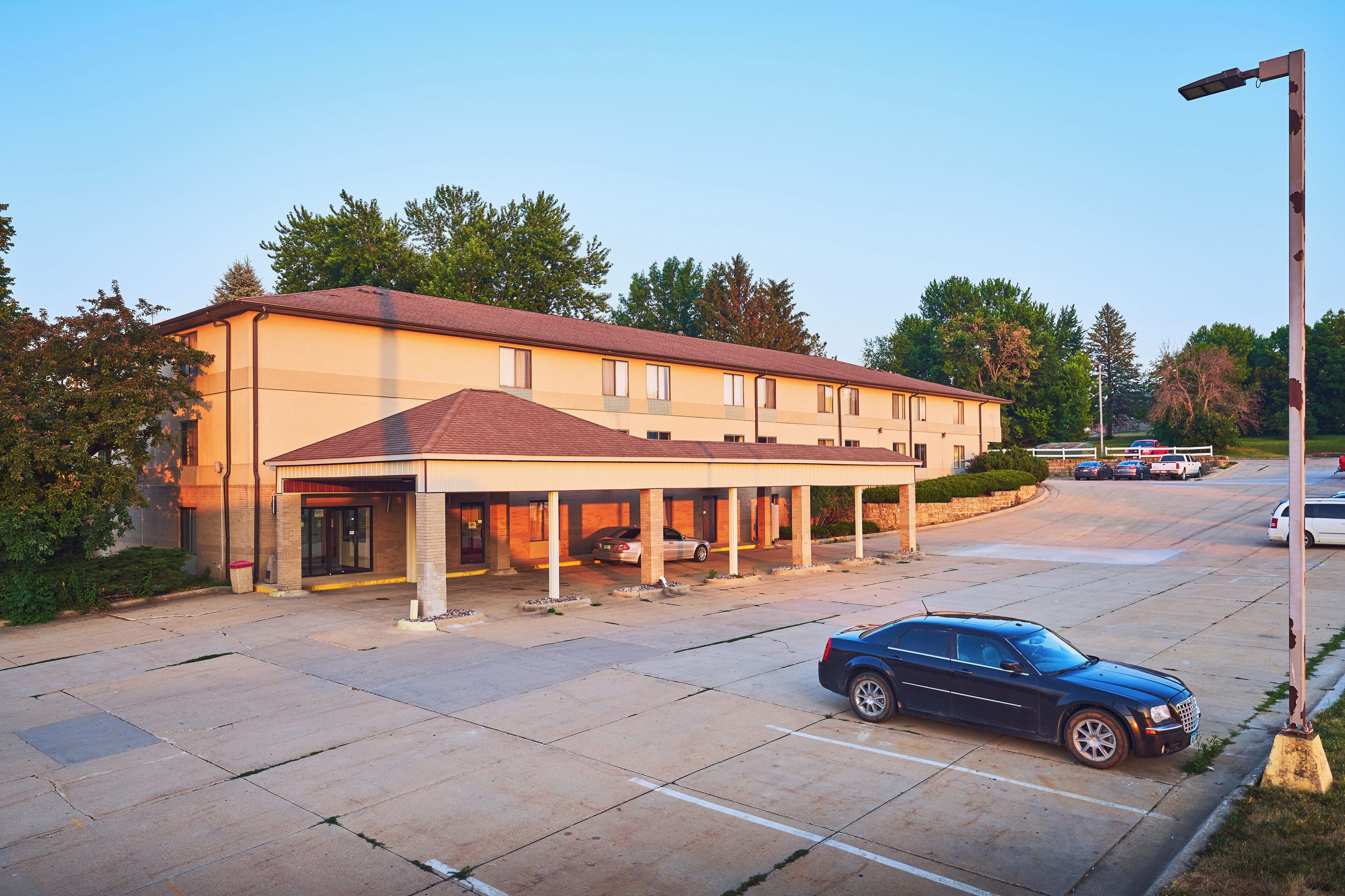 A hotel with a covered parking area and a single-story building.