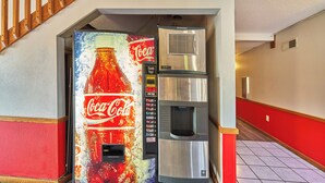 A Coca-Cola vending machine and a stainless steel refrigerator in a hallway with red and white walls. - Econo Lodge Maquoketa (Maquoketa)
