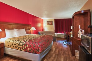 A hotel room with a large bed, a desk, a chair, a microwave, and a trash bin. - Econo Lodge Maquoketa (Maquoketa)
