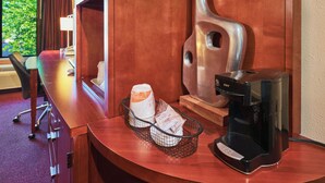 A hotel room with a wooden desk, a coffee maker, and a basket with toiletries. - Econo Lodge Maquoketa (Maquoketa)