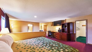 A hotel room with a large bed, a desk, a chair, a television, and a wardrobe. - Econo Lodge Maquoketa (Maquoketa)